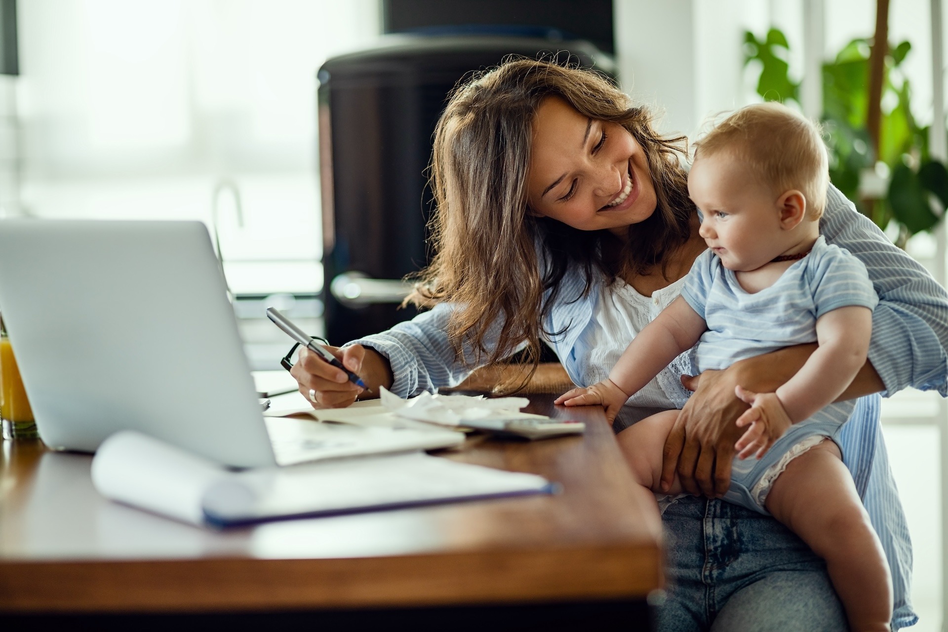 paid-maternity-leaves-pamgro Young happy mother going through home finances and communicating with her baby son.