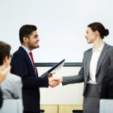 Coach congratulating one of business course attendants on graduation event