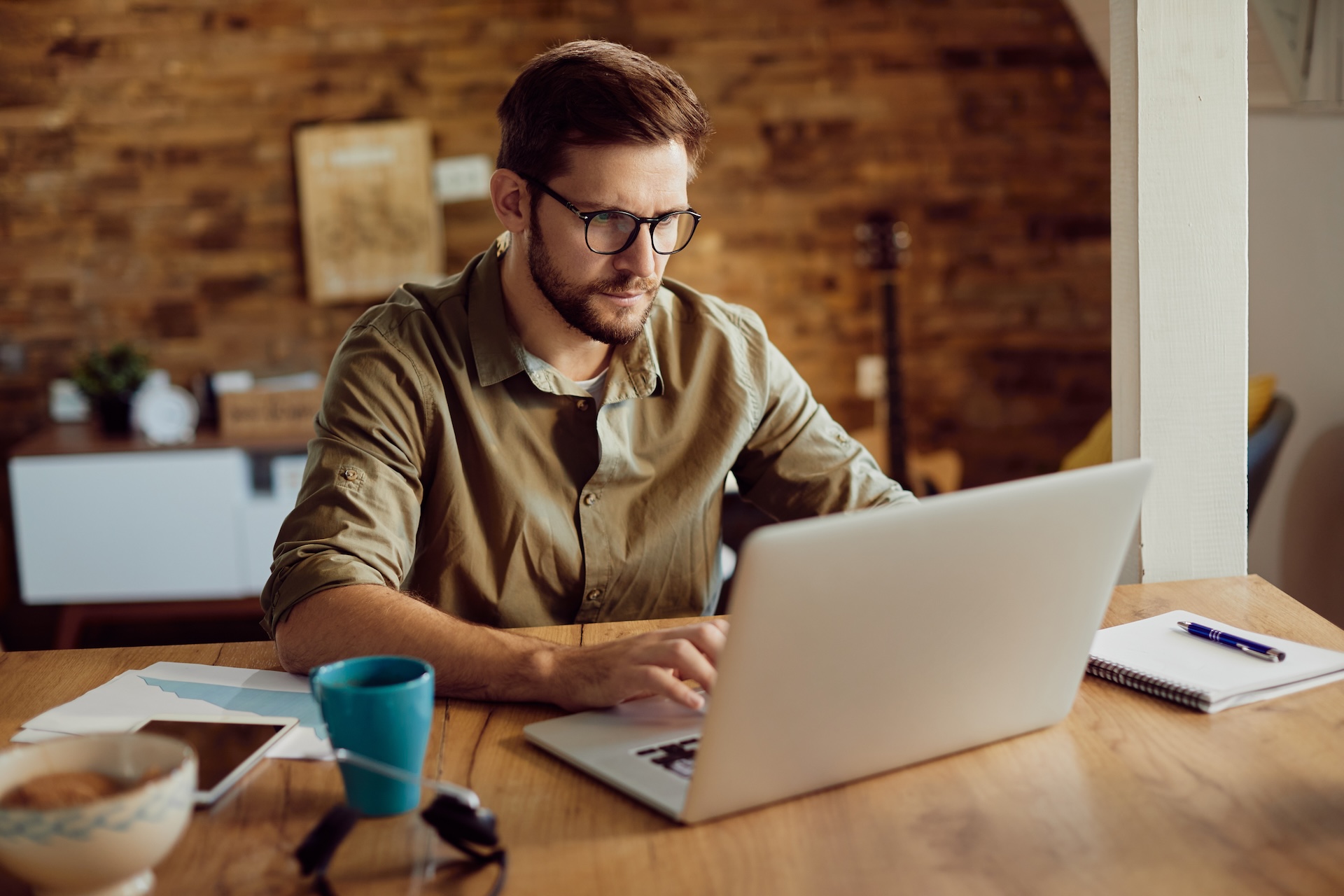 Freelance worker using laptop and typing an e-mail while working at home.